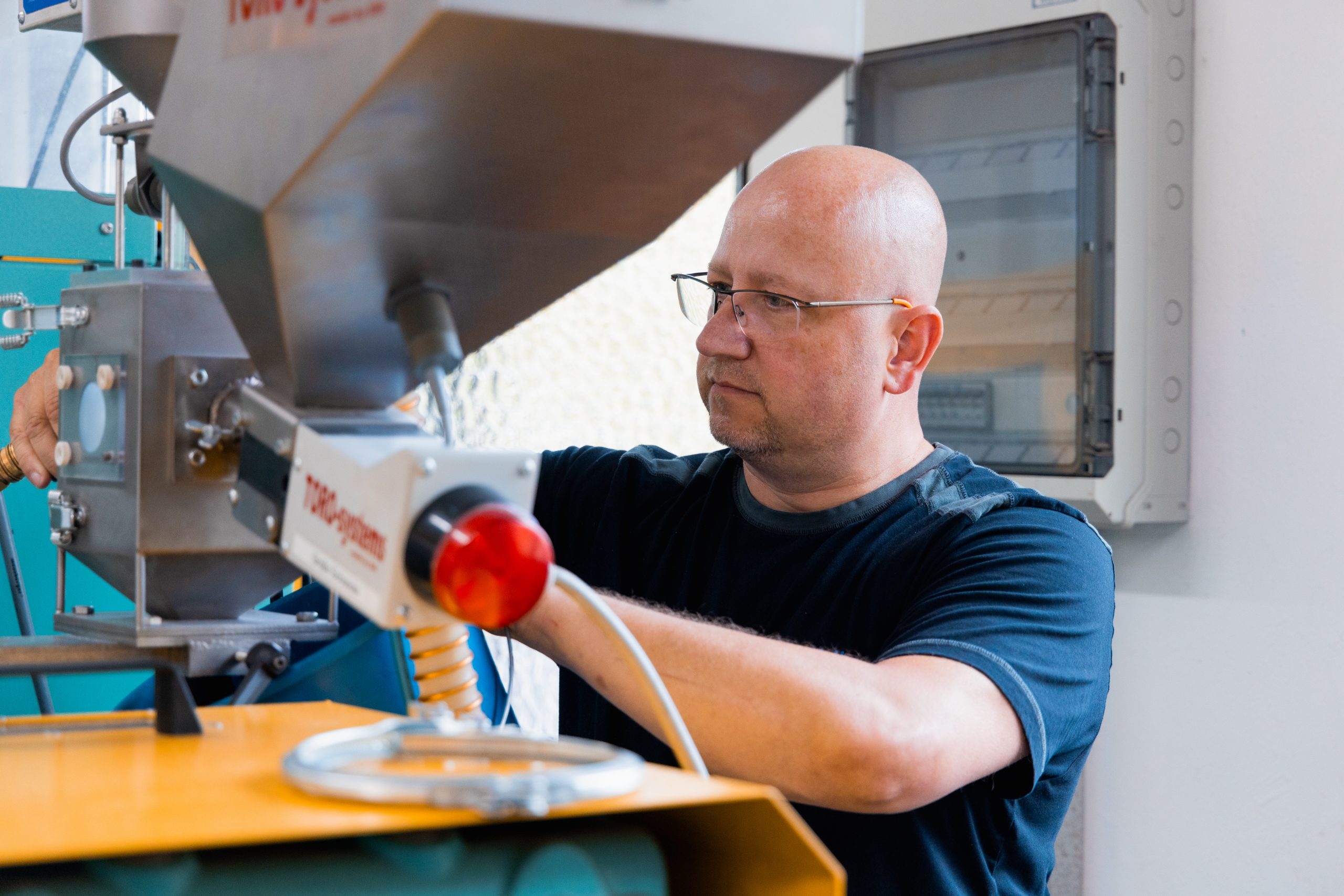 Mitarbeiter reinigt die Produktionsanlage und justiert sie